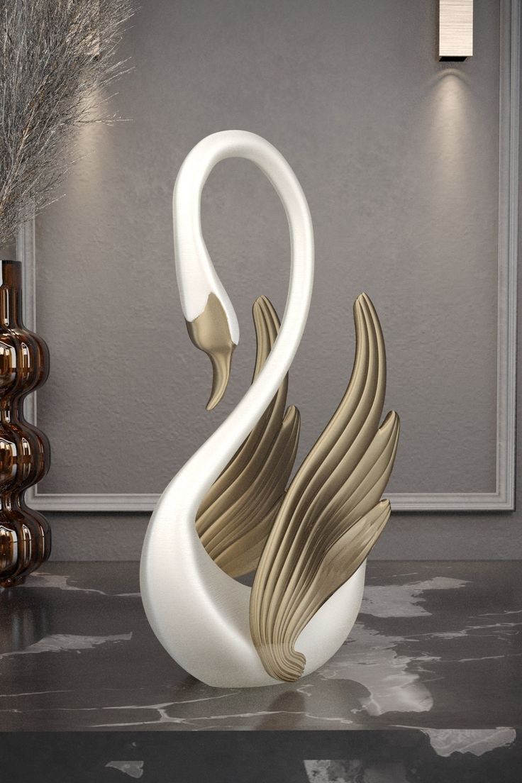 a white and gold swan sculpture sitting on top of a table next to vases