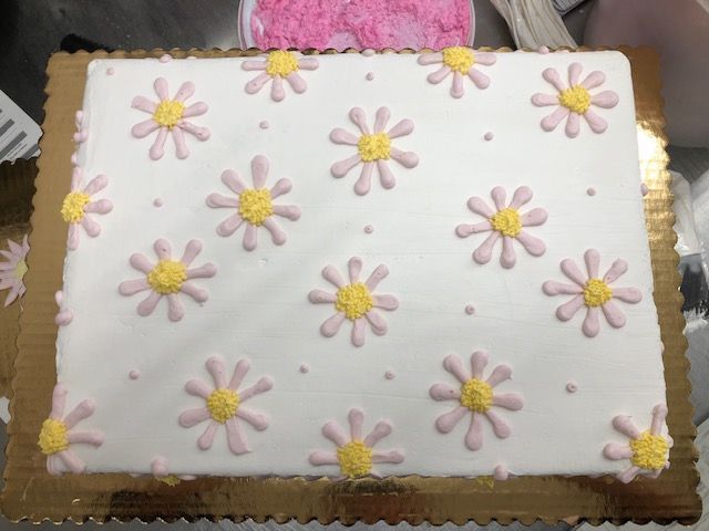 a cake with pink frosting and yellow flowers on it, sitting on a table