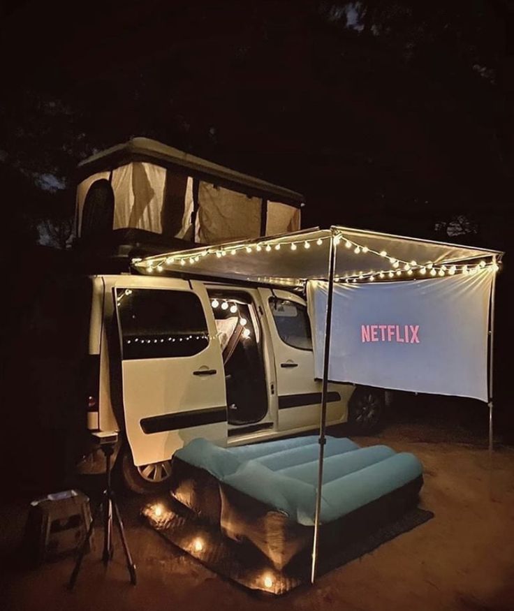 a white truck parked next to a tent with lights on it