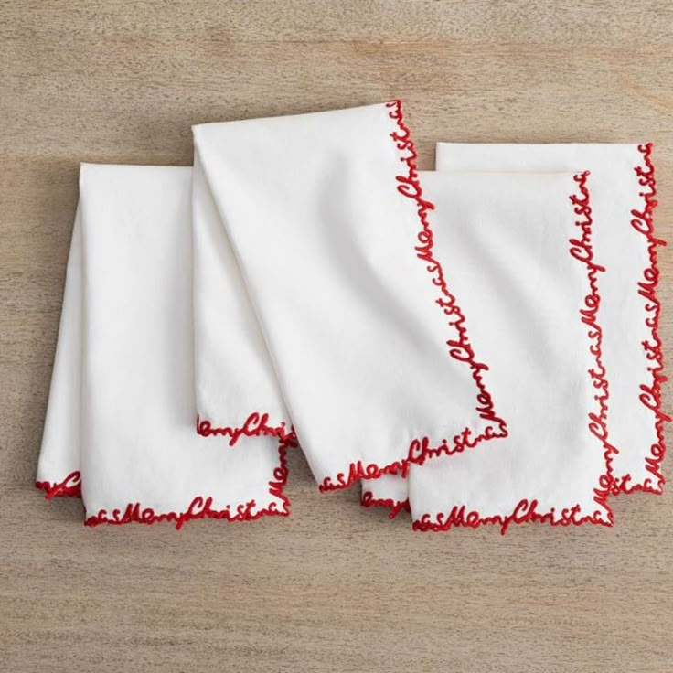 four red and white napkins on top of a wooden table next to each other