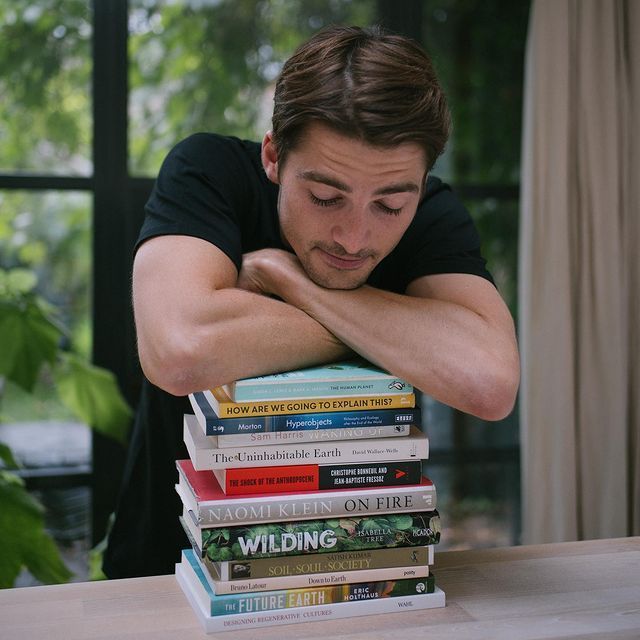 a man leaning his head on a stack of books