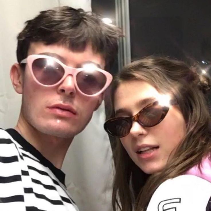 a young man and woman wearing sunglasses posing for a photo in front of a mirror