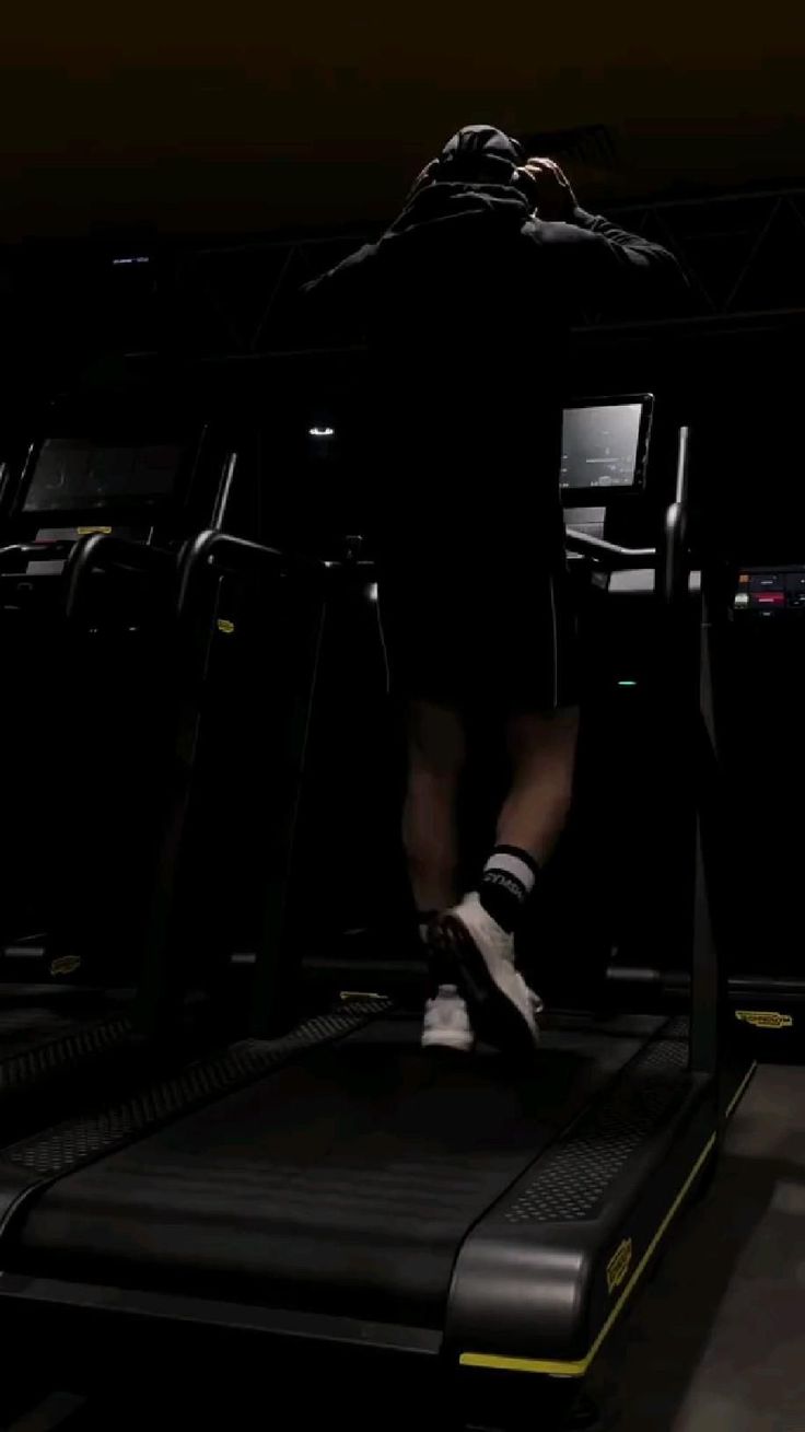 a man is running on a treadmill in the dark, with his feet up