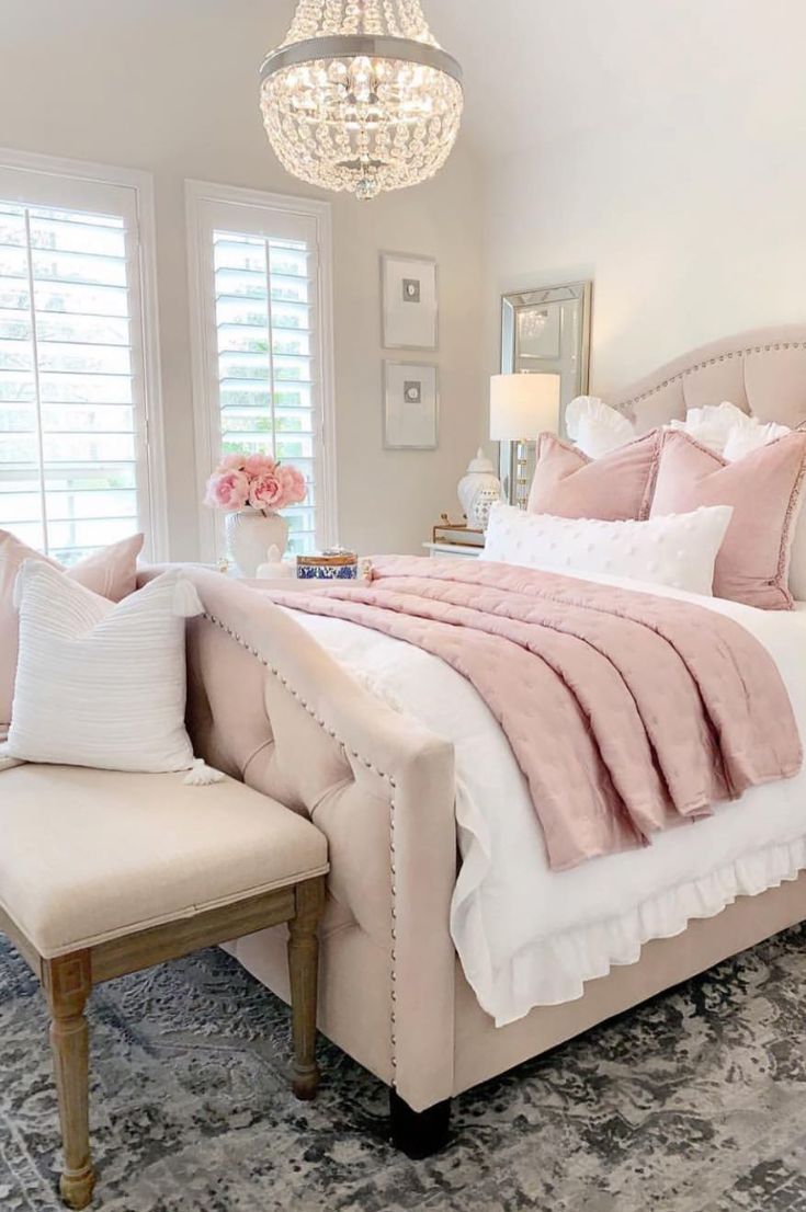 a bedroom with a large bed, chandelier and pillows on the headboard