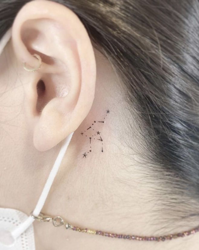 a woman's behind the ear has a small star tattoo on her left side