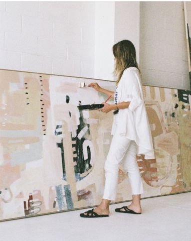 a woman standing in front of a large painting