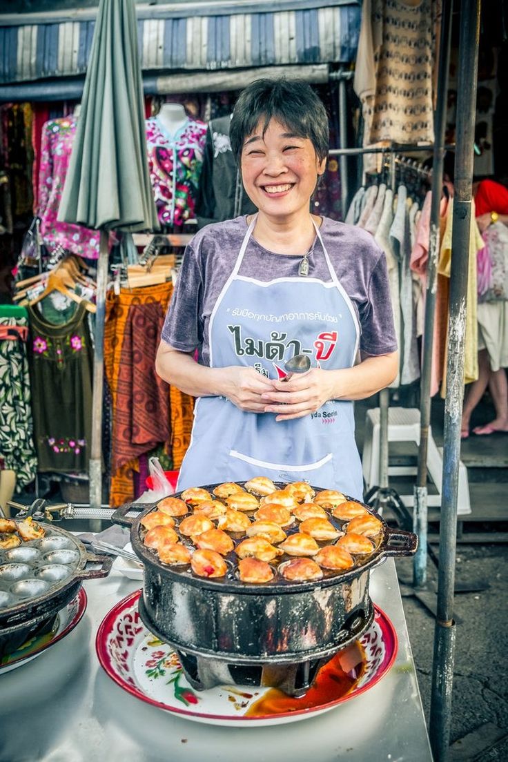 a woman standing in front of a large pot full of food