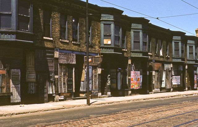 an empty street in front of old buildings with boarded up windows and signs on them