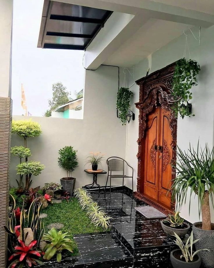 an outdoor patio with potted plants on the ground and a wooden door in the background