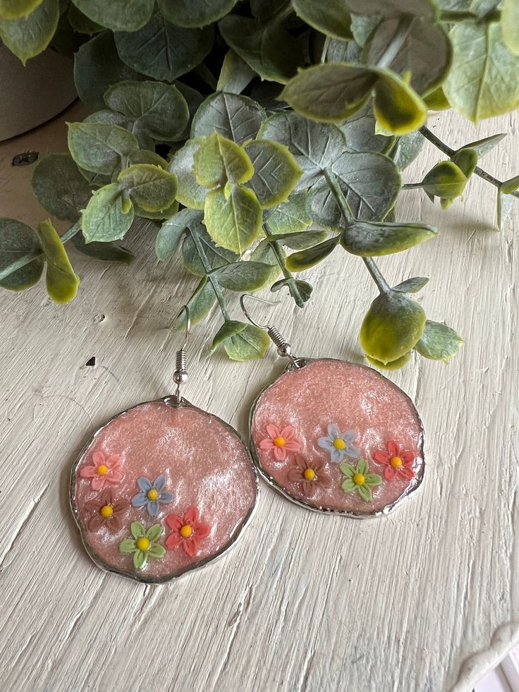 Resin earrings set in a silver colored metal bezel. Hang about 2 1/2". Light shimmery pink background. Perfect for the spring and summer. Pink Flower Metal Earrings, Pink Flower-shaped Metal Earrings, Pink Metal Drop Flower Earrings, Pink Earrings With Ear Wire For Spring, Pink Metal Earrings For Spring, Silver Earrings For Spring Party, Silver Earrings For Party In Spring, Nickel Free Jewelry For Spring Party, Nickel-free Jewelry For Spring Parties