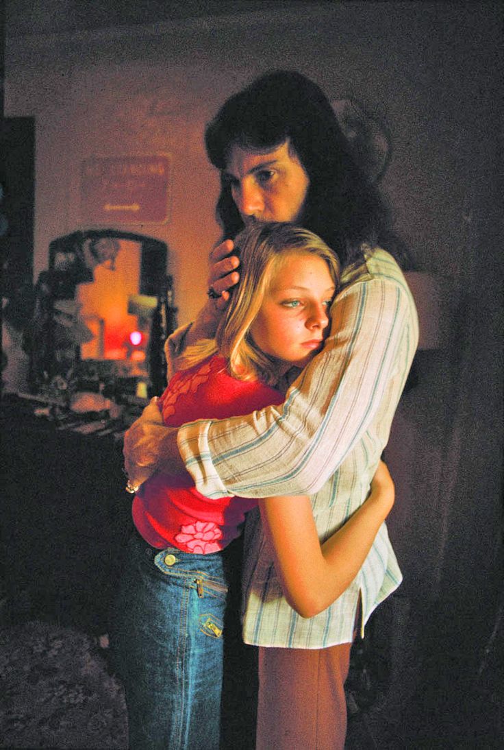 two young women embracing each other in the dark, one is wearing a red shirt