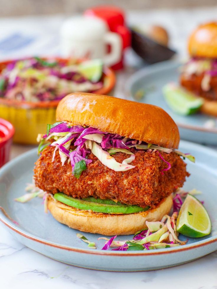 a fried chicken sandwich on a bun with coleslaw and slaw in the background