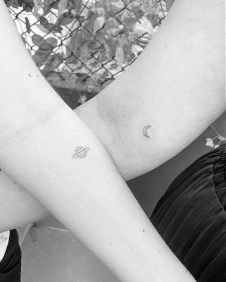 black and white photo of two people with tattoos on their arms, one holding the other's arm