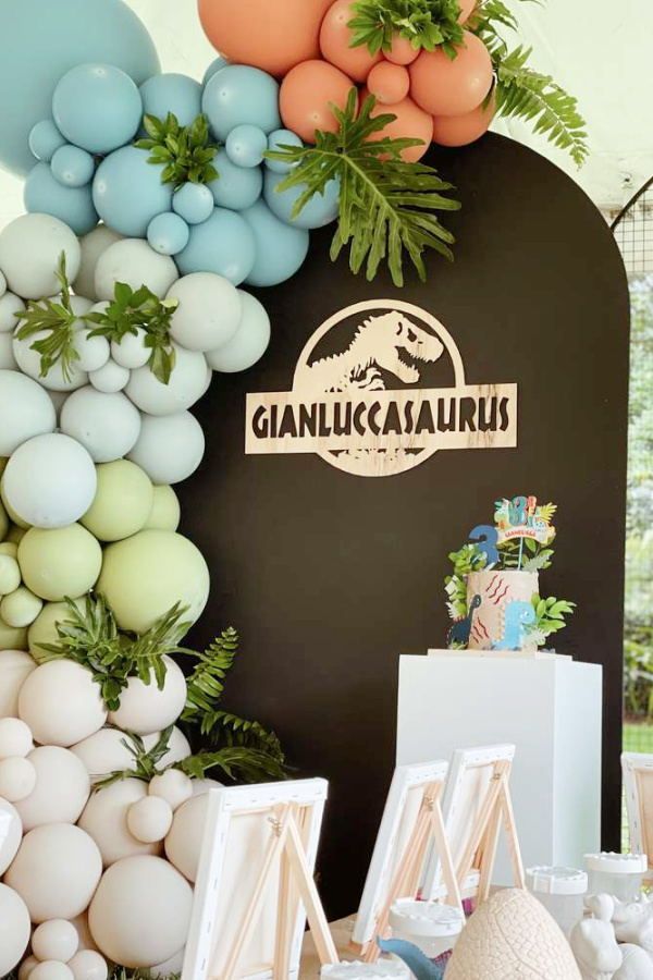 an assortment of balloons and decorations on display at a dinosaur themed birthday party with the name gannukauarus