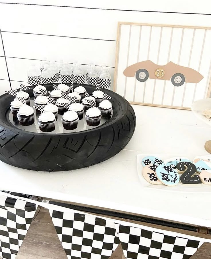 a table topped with cupcakes on top of a plate next to a tire