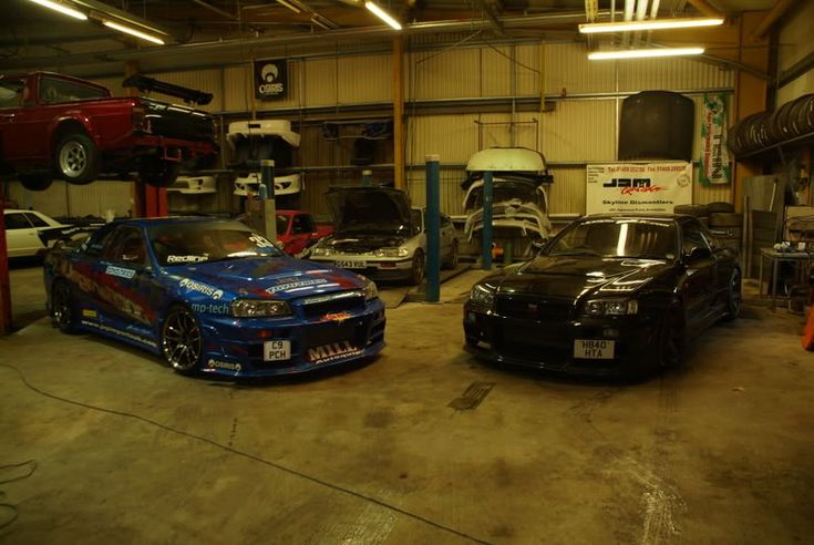 two cars parked in a garage next to each other with their hoods up and tires down