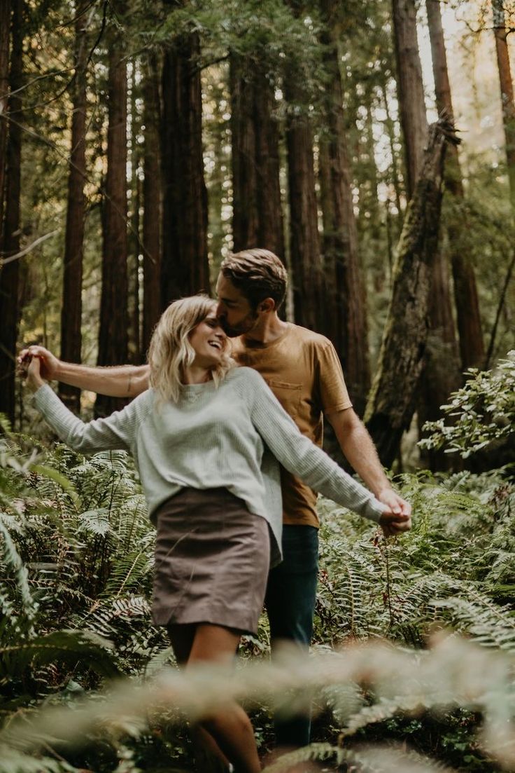 a man and woman are walking through the woods