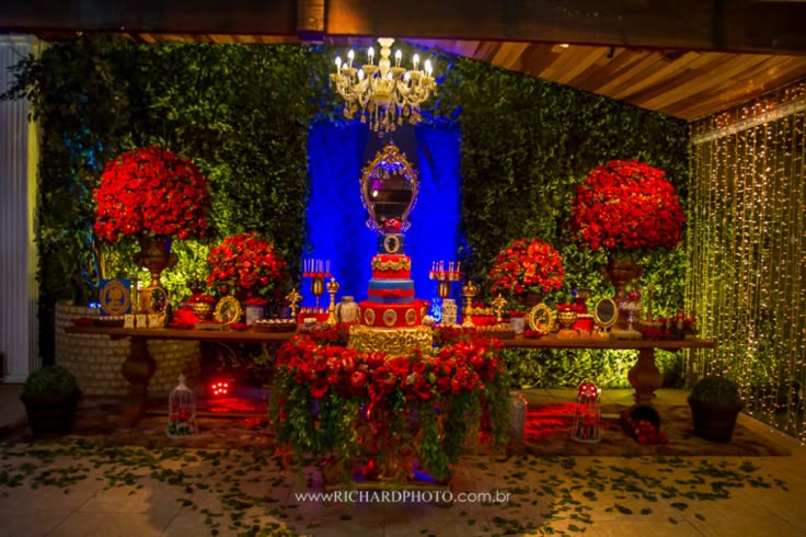 a table with red flowers and candles on it