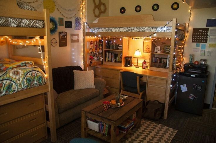 a dorm room with bunk beds, desks and lights on the ceiling above it