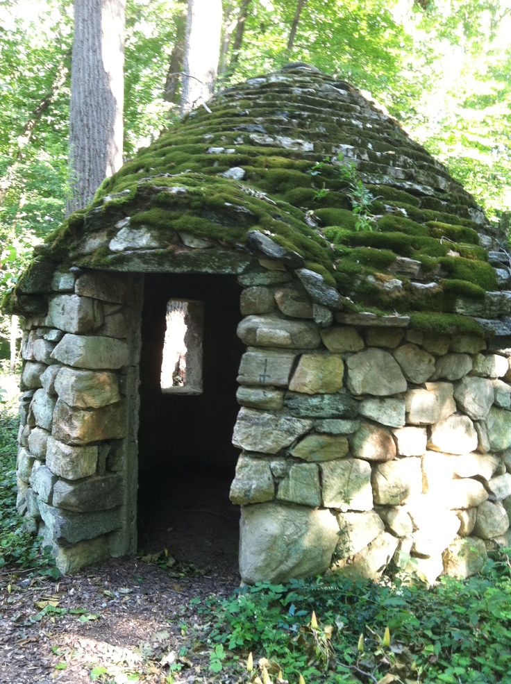 an old stone building with moss growing on it's roof in the middle of a forest