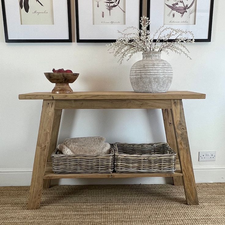 a wooden table with two baskets on top of it and pictures hanging above the table