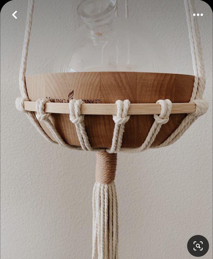 a wooden bowl with rope hanging from it's sides and a glass dome on top