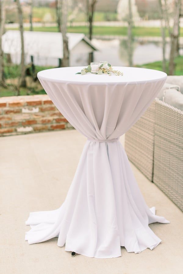 a table with white cloth draped over it and some flowers on the top is sitting outside