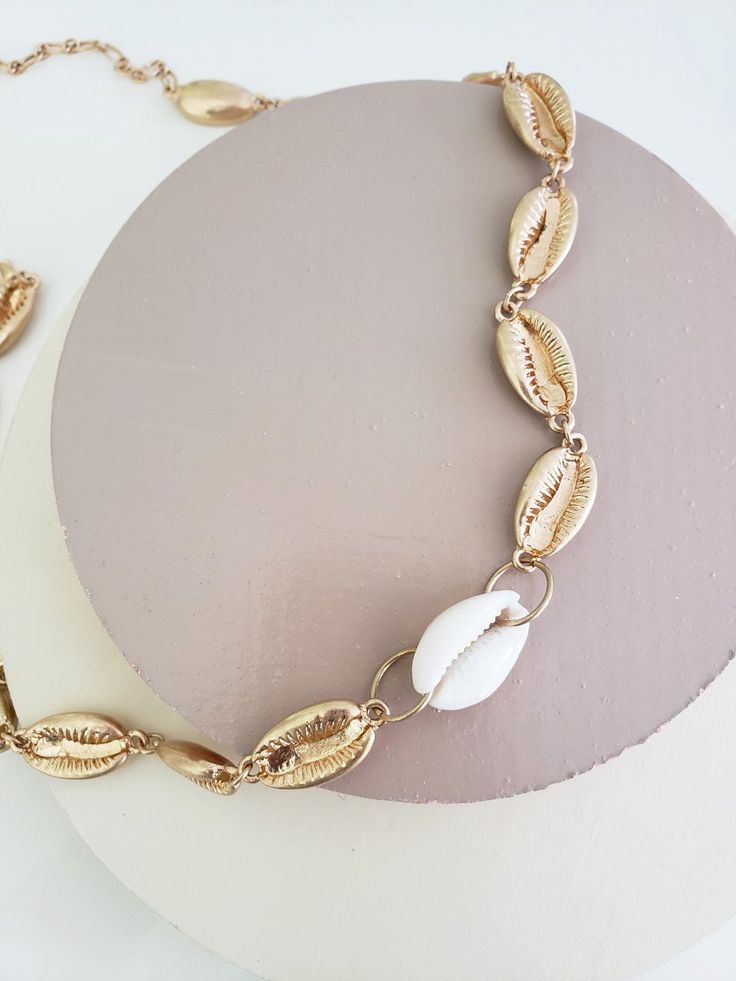 Channel your inner boho beach babe with the Samantha Puka Shell Necklace, a captivating accessory that brings a touch of the ocean to your style. This necklace features a single strand of gold puka shell chain adorned with a natural puka shell accent, evoking a sense of beachy charm and laid-back elegance. The natural texture and unique shape of the puka shell add an organic and earthy element to your ensemble. Whether you're strolling along sandy shores or simply want to infuse your everyday lo Sea Shell Necklace, Puka Shell Necklace, Sandy Shores, Puka Shell, Seashell Necklace, Shell Necklace, Shell Necklaces, Boho Beach, Beach Babe