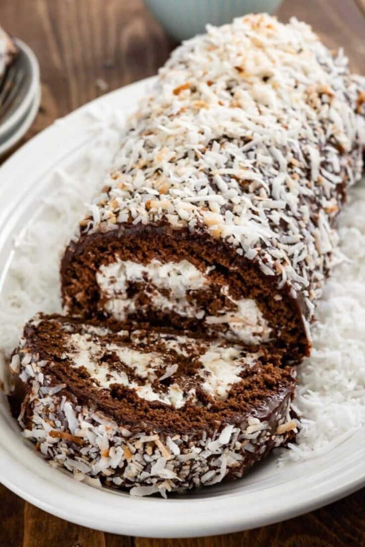 there is a chocolate roll on the plate with coconut sprinkles around it