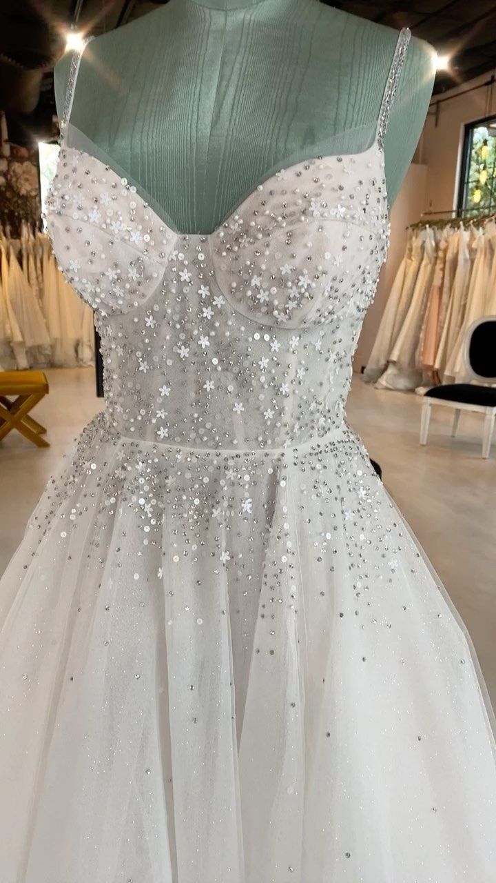 a white dress with silver sequins is on display in a store window,