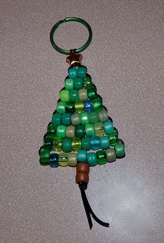 a christmas tree made out of glass beads on a keychain with a leather cord