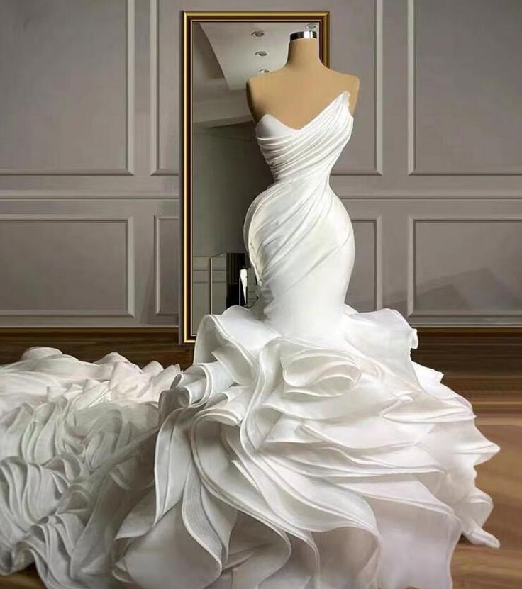 a white wedding dress sitting on top of a wooden floor next to a mannequin