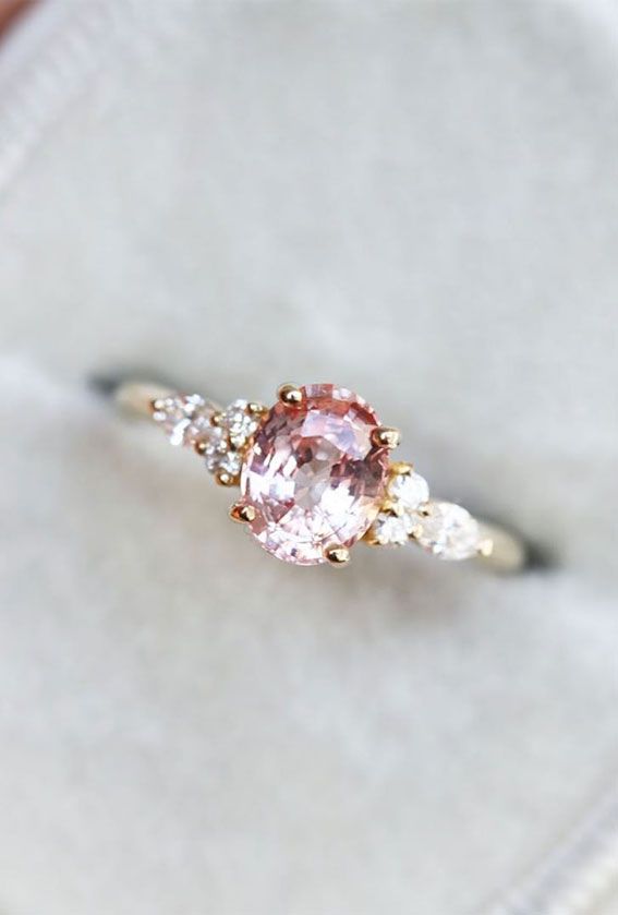 a pink diamond ring sitting on top of a white cloth