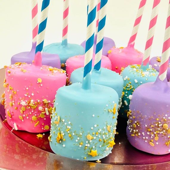 there are many cake pops with candles in them on the plate and one has sprinkles