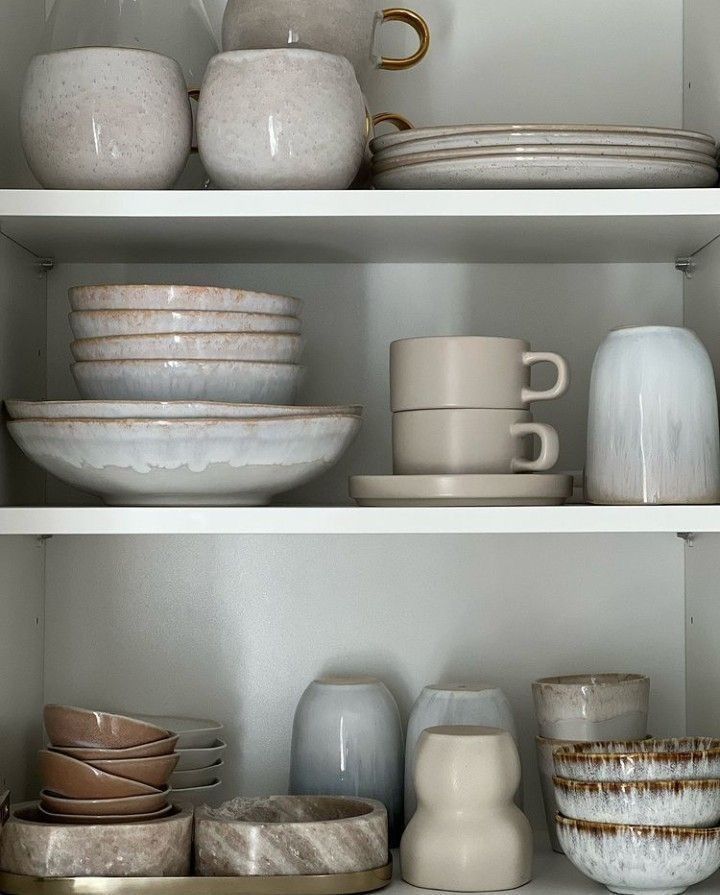 the shelves are filled with dishes and cups