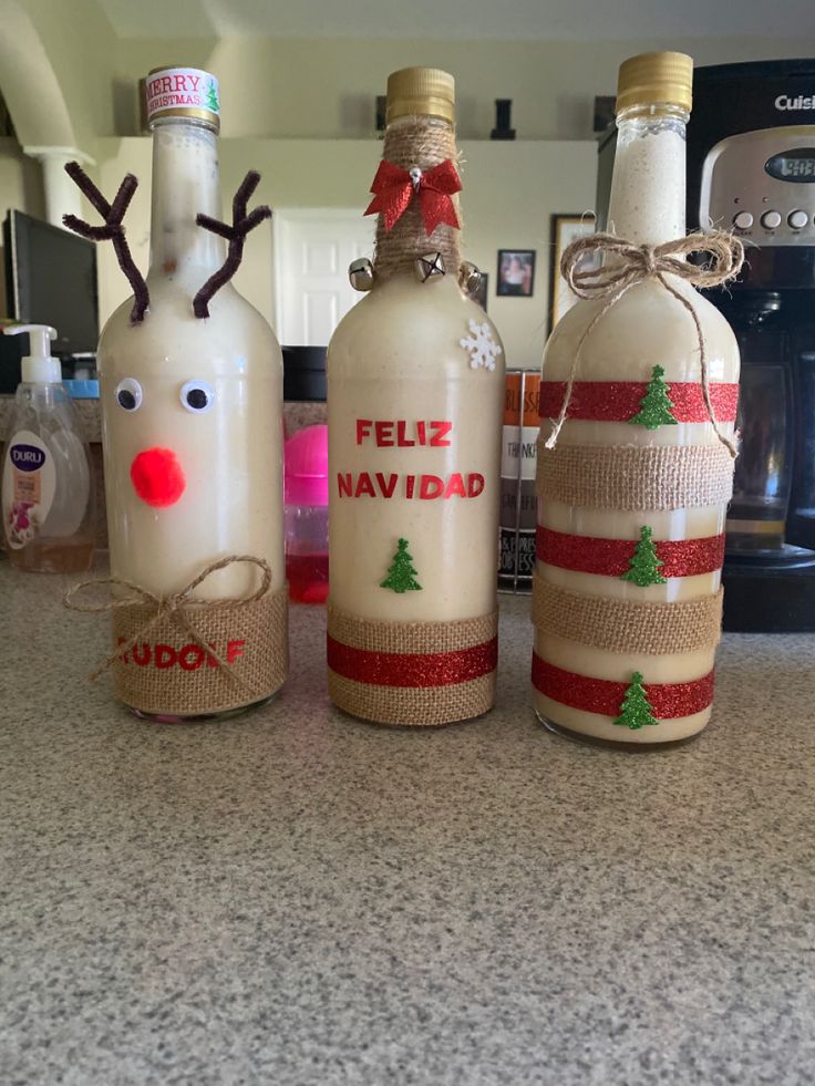 three bottles are decorated with reindeer noses and burlocks for the holiday season, sitting on a kitchen counter