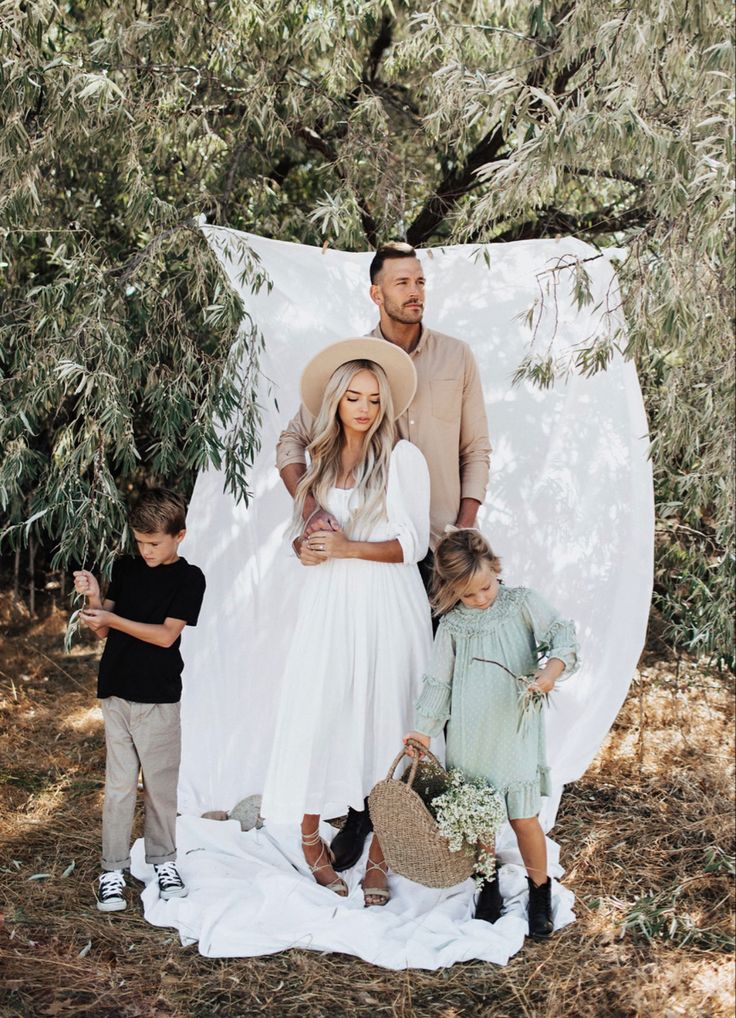 a man and two children are standing in front of an outdoor backdrop with white sheets