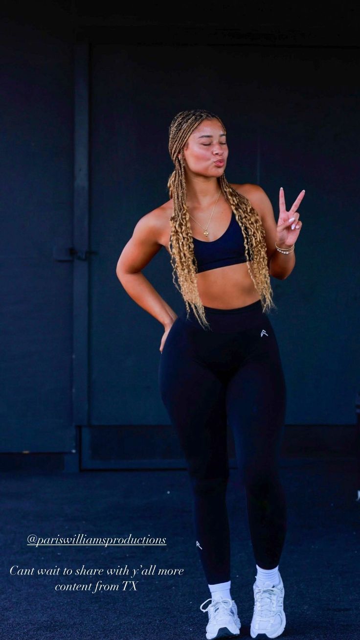 a woman in black sports bra top and leggings standing with her hand up