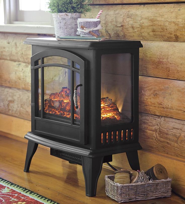 a wood burning stove sitting on top of a hard wood floor next to a window