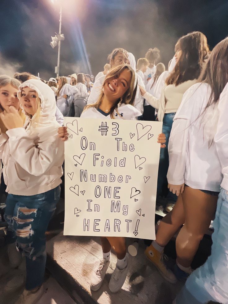 two girls holding up a sign that says on the field number one in my heart