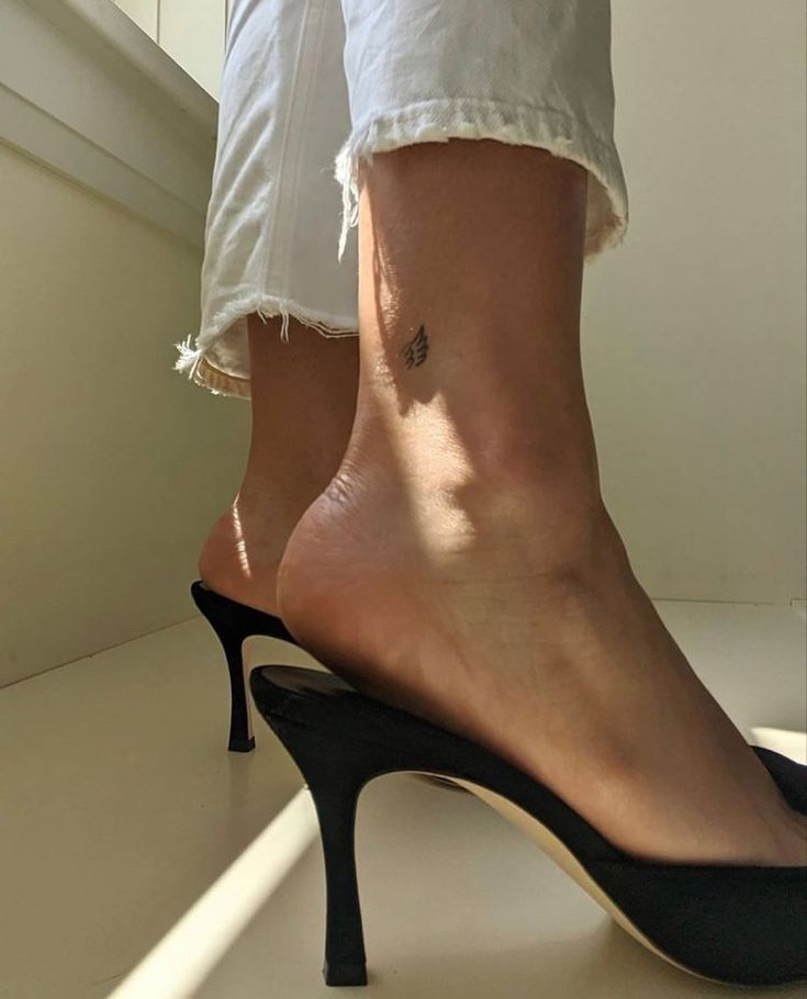 a woman's legs with tattoos on her left ankle and right leg in high heels