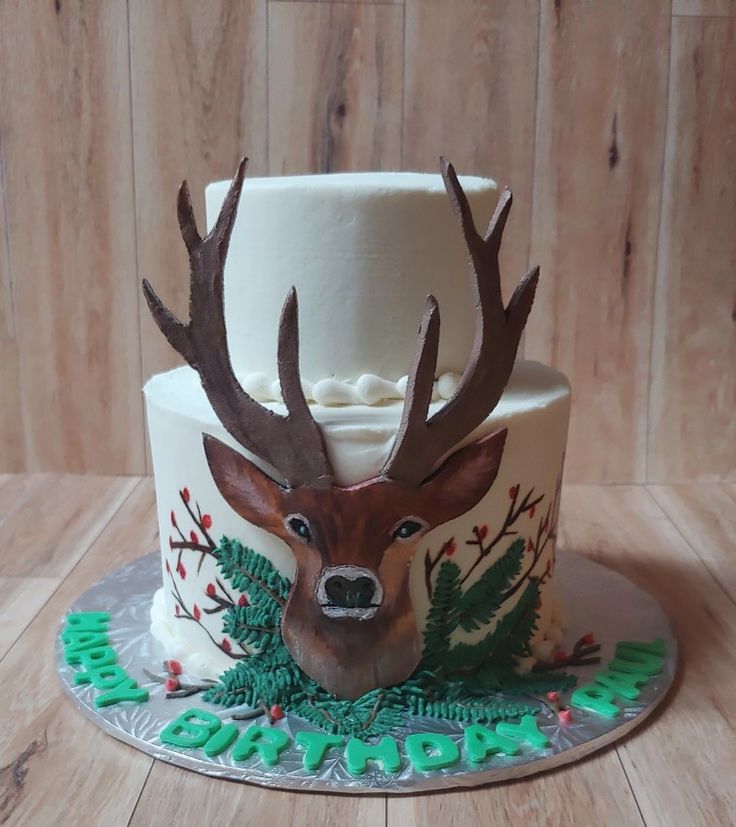 a cake decorated with deer's head and evergreen leaves