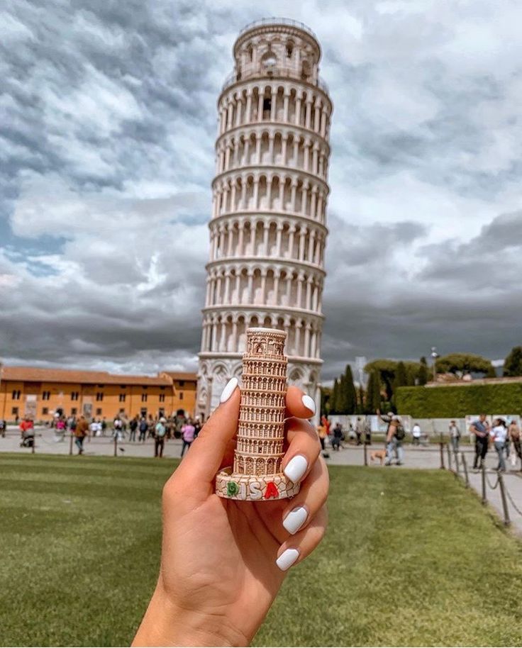 a hand holding up a miniature model of the leaning tower