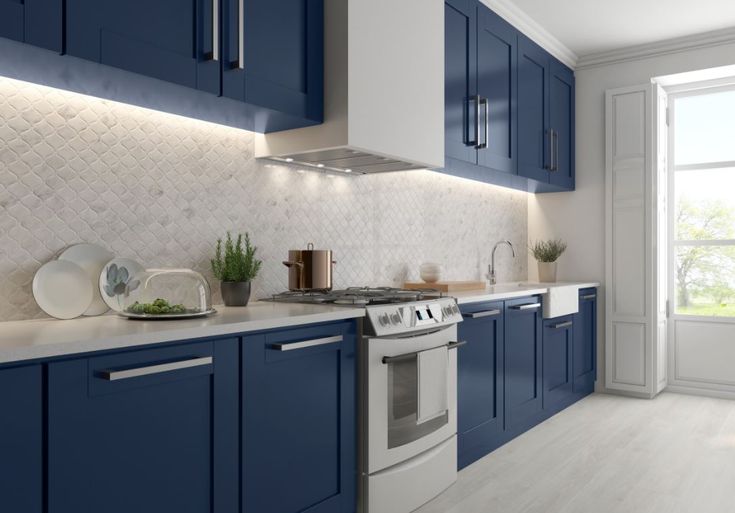 a kitchen with blue cabinets and white counter tops is pictured in this image, there are plates on the stove