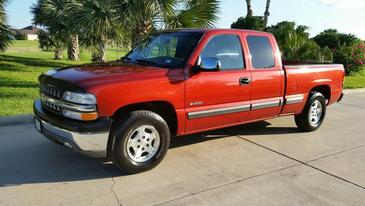 a red pick up truck parked in front of palm trees