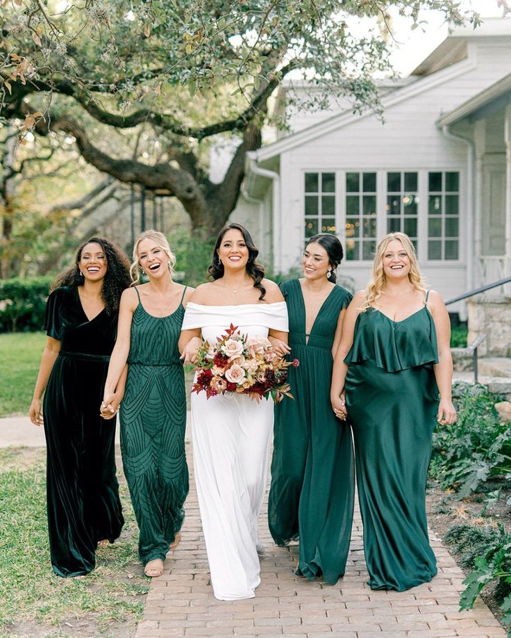 a group of women standing next to each other in front of a house wearing green dresses