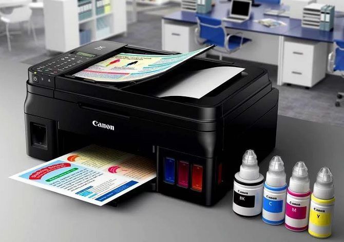 a printer and ink bottles on a table