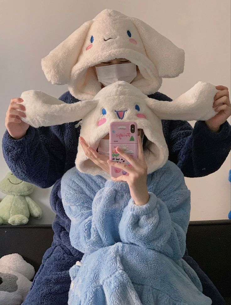 a person wearing a bunny costume holding a cell phone in front of their face with stuffed animals around them