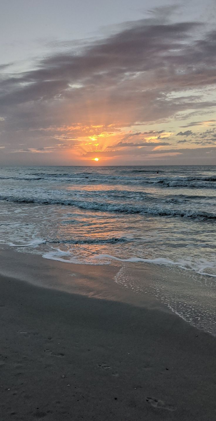 the sun is setting over the ocean with waves