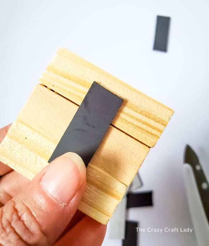 a hand holding a small piece of wood with a black object in the middle of it